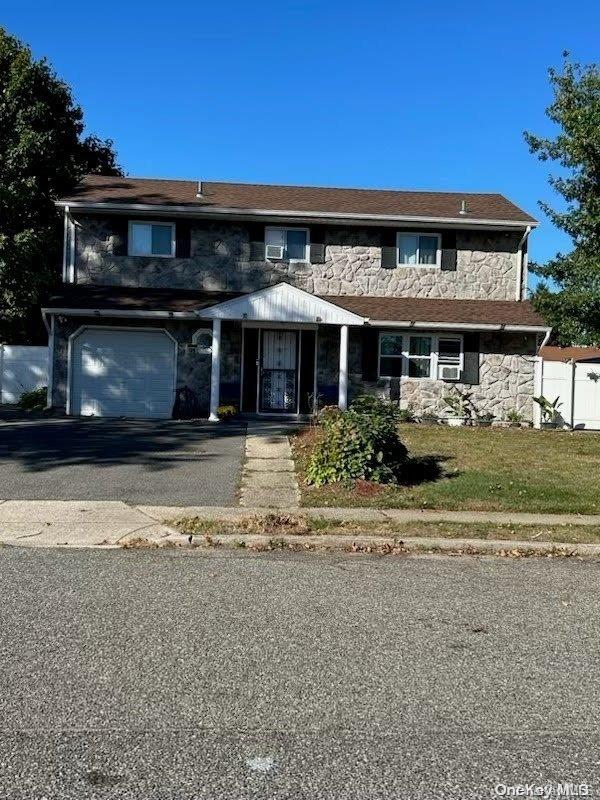 136 Acorn Ave, Central Islip, NY 11722 - view of front facade featuring stone siding, an attached garage, and asphalt driveway