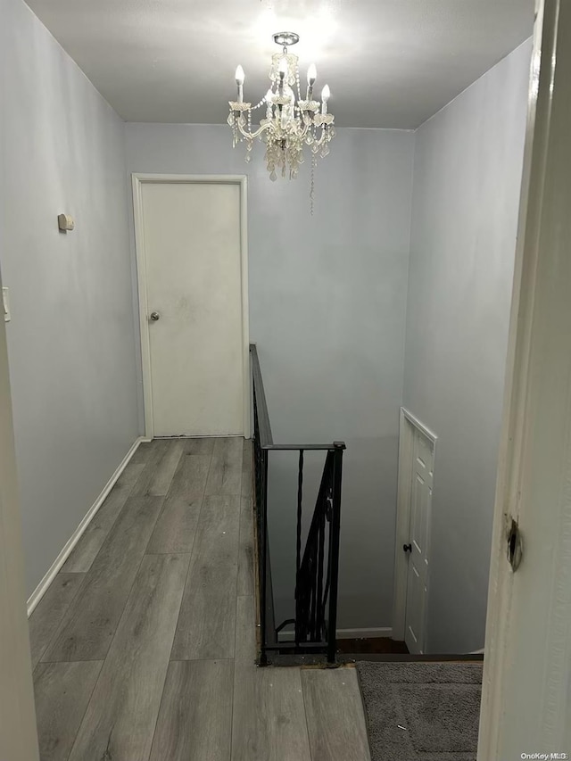 staircase with wood-type flooring and a notable chandelier