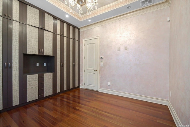 empty room featuring crown molding, dark wood-type flooring, and a notable chandelier