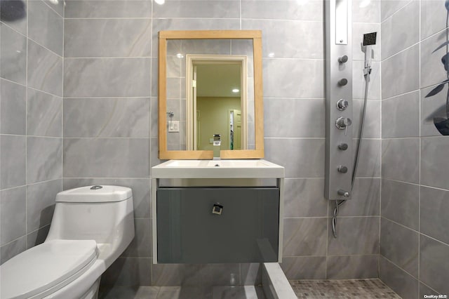 bathroom featuring vanity, toilet, tile walls, and a tile shower