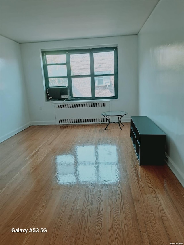 empty room featuring radiator heating unit, a healthy amount of sunlight, and light hardwood / wood-style floors