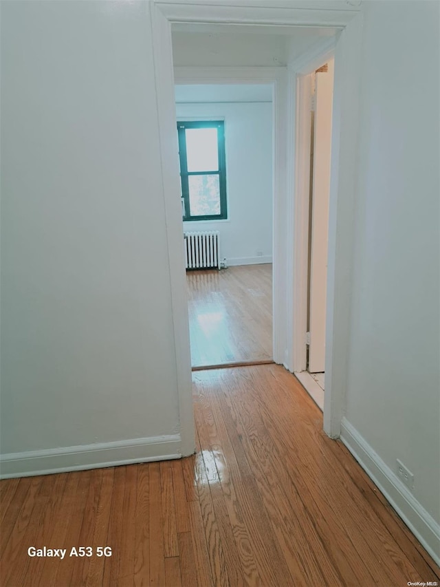 hallway with light wood-type flooring and radiator