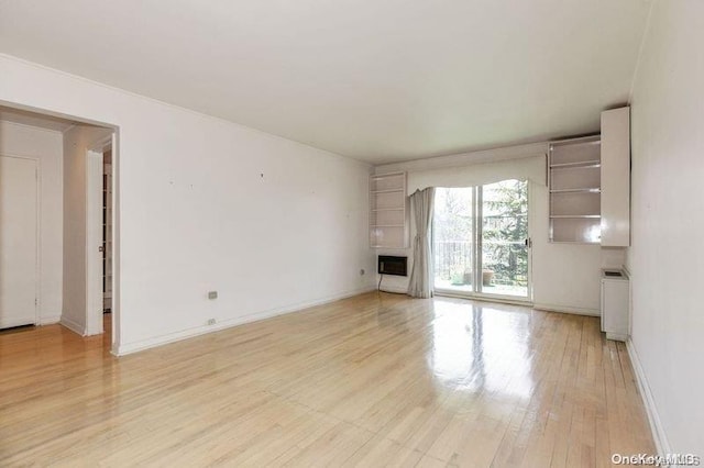 unfurnished living room featuring heating unit, radiator heating unit, a fireplace, and light hardwood / wood-style flooring