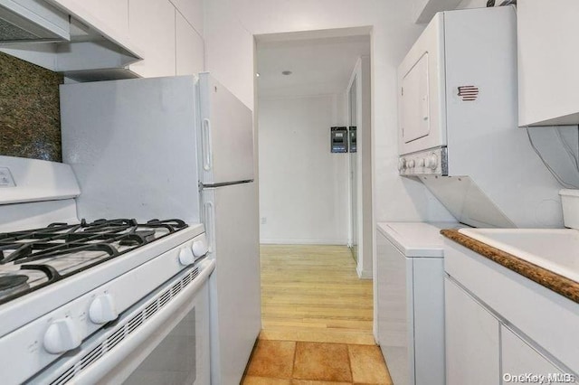 kitchen featuring light hardwood / wood-style flooring, stacked washer / dryer, white cabinetry, white gas stove, and range hood