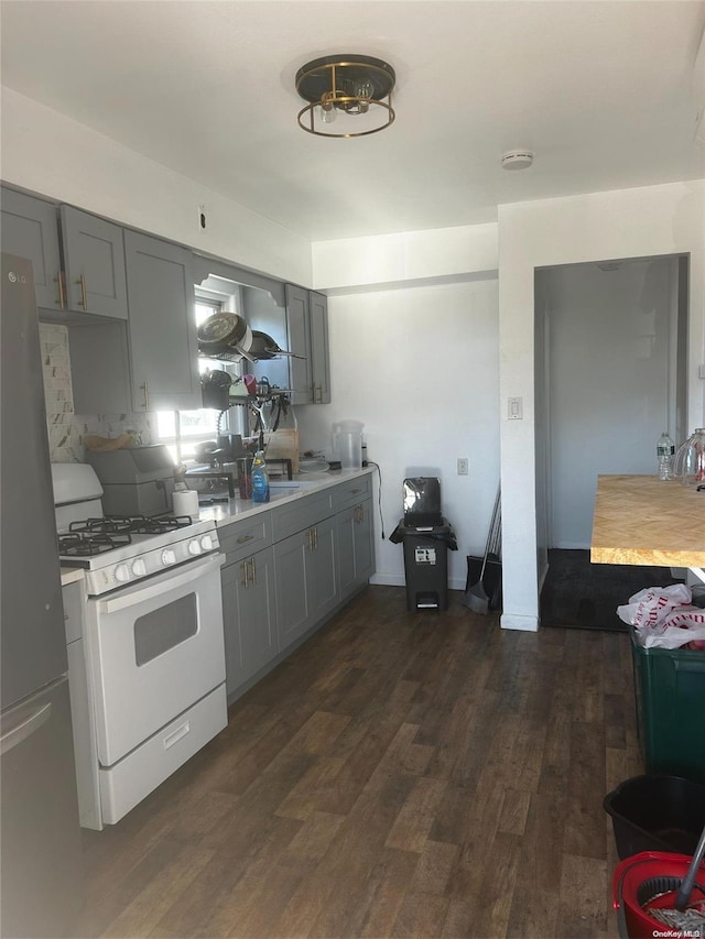 kitchen with white gas stove, range hood, dark hardwood / wood-style floors, stainless steel fridge, and gray cabinets