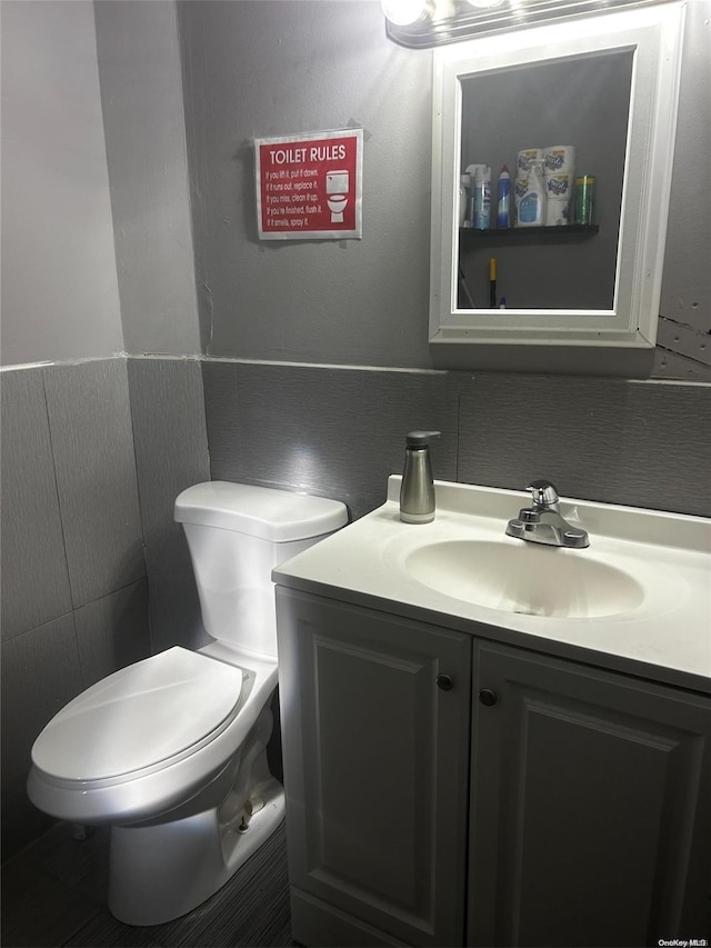 bathroom featuring vanity, toilet, and tile walls