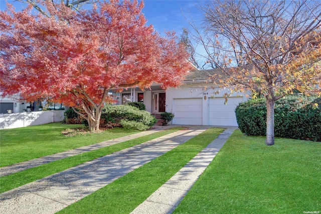 view of property hidden behind natural elements featuring a garage and a front lawn