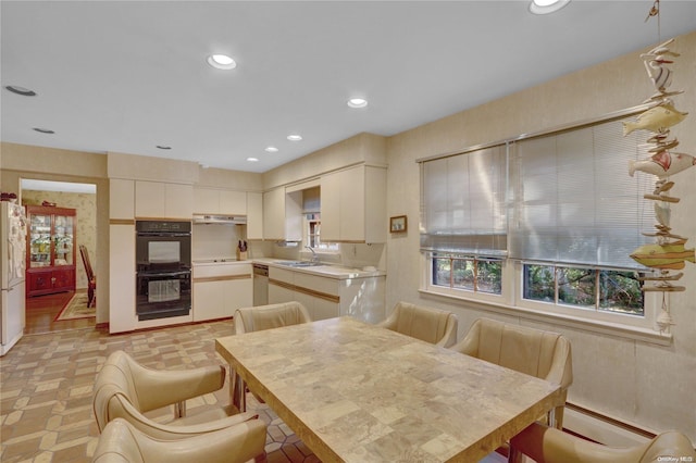 kitchen with black double oven, sink, white refrigerator, dishwasher, and white cabinetry