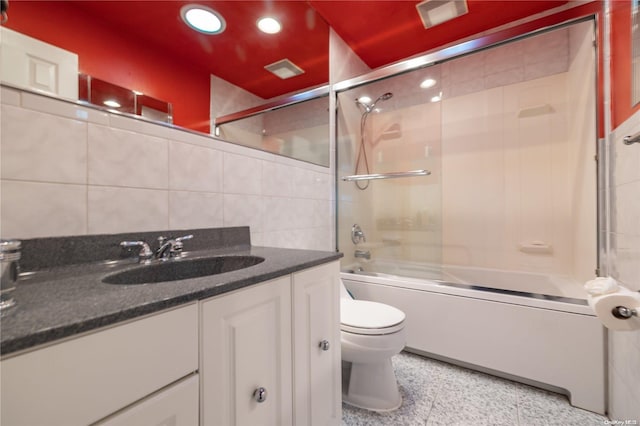 full bathroom featuring vanity, toilet, tile walls, and enclosed tub / shower combo