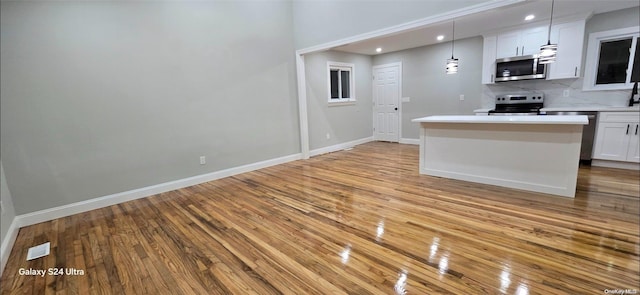 kitchen with white cabinetry, pendant lighting, stainless steel appliances, and light hardwood / wood-style flooring