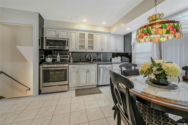 kitchen with decorative backsplash, appliances with stainless steel finishes, sink, light tile patterned floors, and gray cabinets