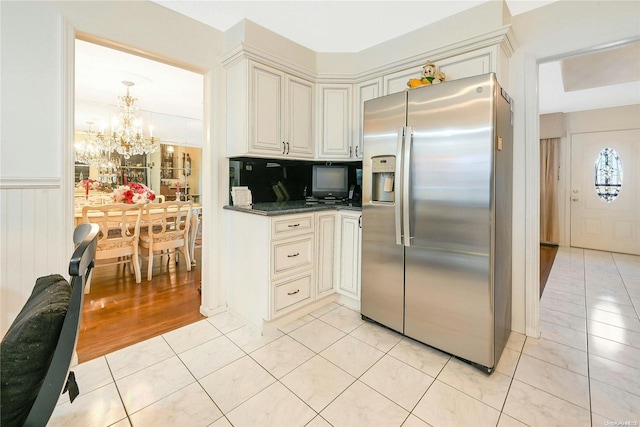 kitchen featuring tasteful backsplash, dark stone counters, light hardwood / wood-style flooring, a notable chandelier, and stainless steel fridge with ice dispenser