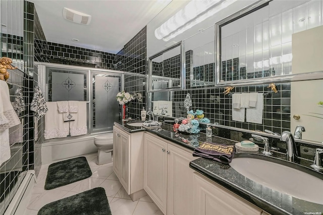 full bathroom with a baseboard heating unit, tile patterned floors, bath / shower combo with glass door, vanity, and tile walls