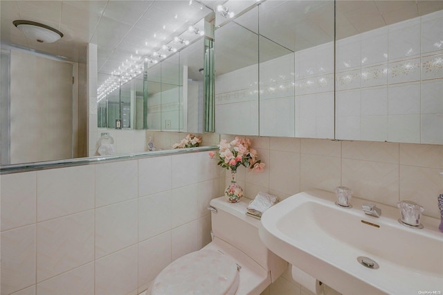 bathroom with tasteful backsplash, sink, a shower with shower door, and tile walls