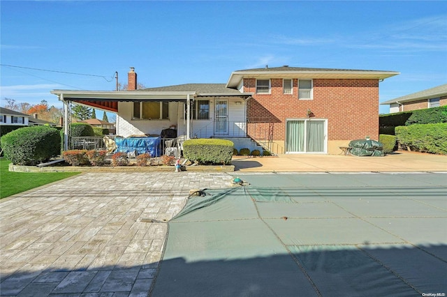 back of property featuring a patio area and a covered pool