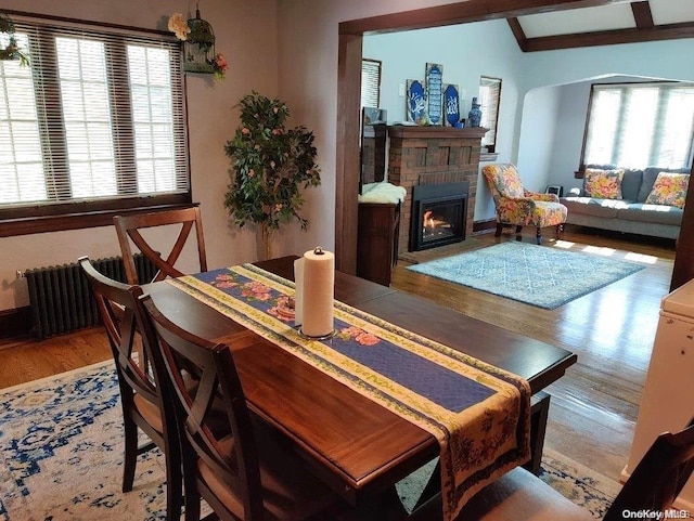 dining space with a fireplace, lofted ceiling with beams, light hardwood / wood-style flooring, and a wealth of natural light