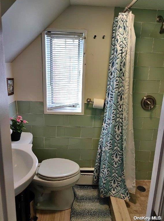 bathroom with sink, vaulted ceiling, a shower with shower curtain, toilet, and tile walls