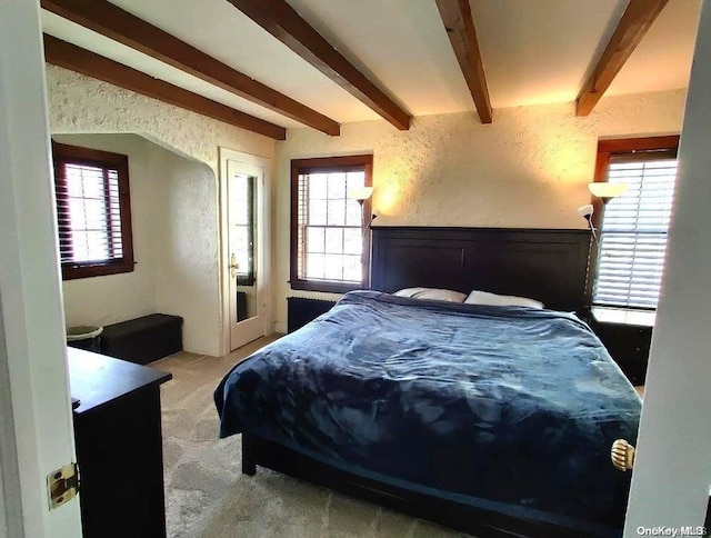 bedroom featuring beam ceiling and light carpet