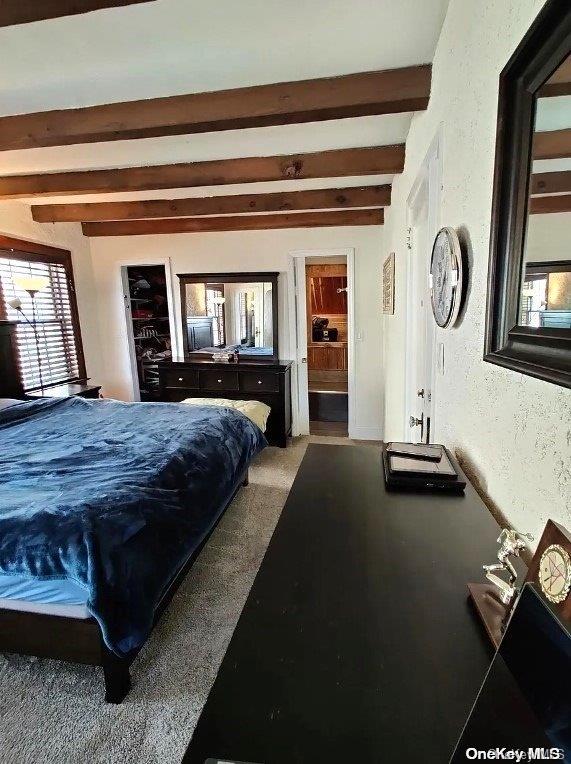 carpeted bedroom with beam ceiling