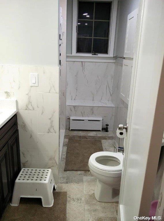 bathroom featuring baseboard heating, vanity, tile walls, and toilet