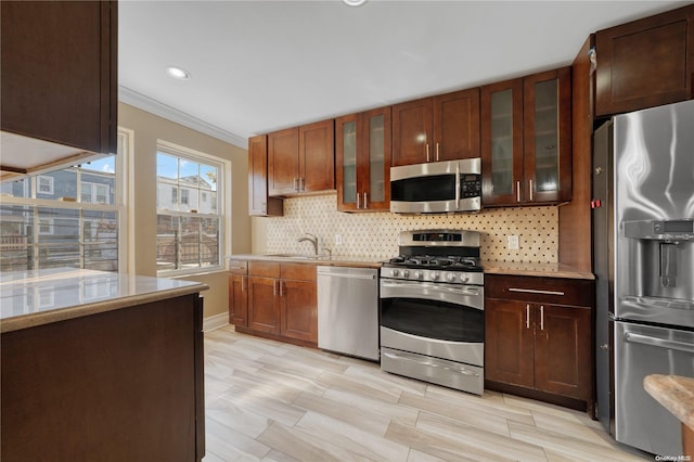 kitchen featuring sink, stainless steel appliances, tasteful backsplash, ornamental molding, and light wood-type flooring