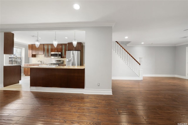 kitchen featuring hanging light fixtures, crown molding, dark wood-type flooring, and appliances with stainless steel finishes