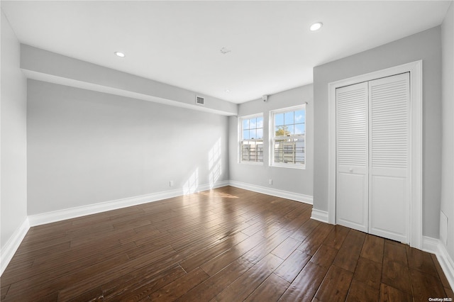 unfurnished bedroom with dark hardwood / wood-style flooring and a closet