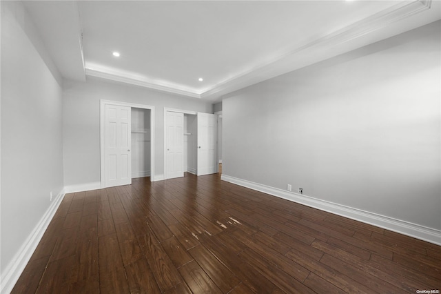 unfurnished bedroom featuring dark hardwood / wood-style floors and a tray ceiling