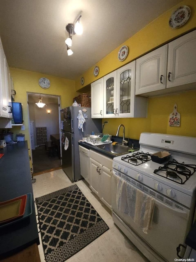 kitchen with white range with gas cooktop, sink, and white cabinets