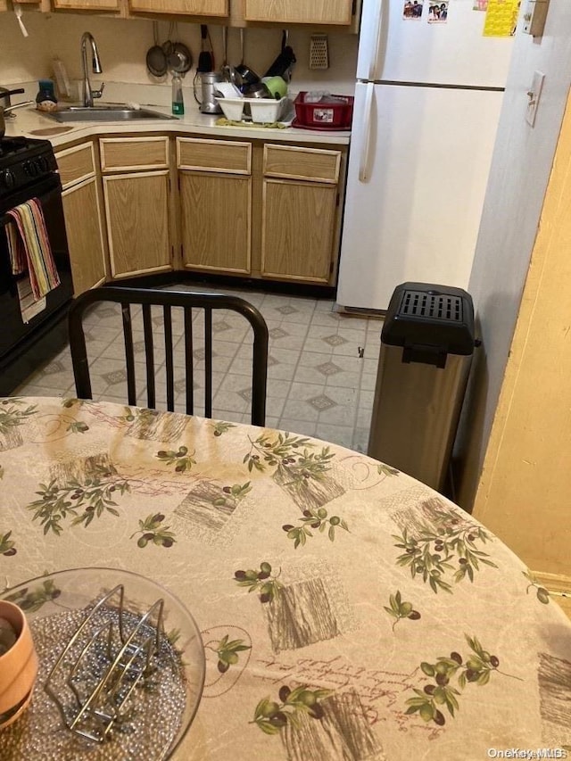 kitchen featuring white refrigerator, black range, and sink