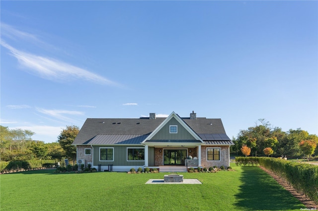 back of house featuring solar panels, a yard, and an outdoor fire pit