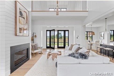 living room with french doors, light hardwood / wood-style flooring, and a high ceiling