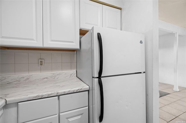 kitchen with white cabinets, light stone countertops, light tile patterned floors, tasteful backsplash, and white fridge