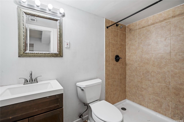 bathroom featuring a tile shower, vanity, and toilet