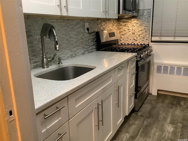 kitchen featuring sink, light stone countertops, appliances with stainless steel finishes, dark hardwood / wood-style flooring, and radiator heating unit