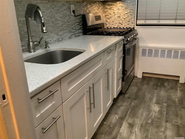 kitchen featuring stainless steel range with gas cooktop, sink, light stone countertops, dark hardwood / wood-style flooring, and radiator heating unit