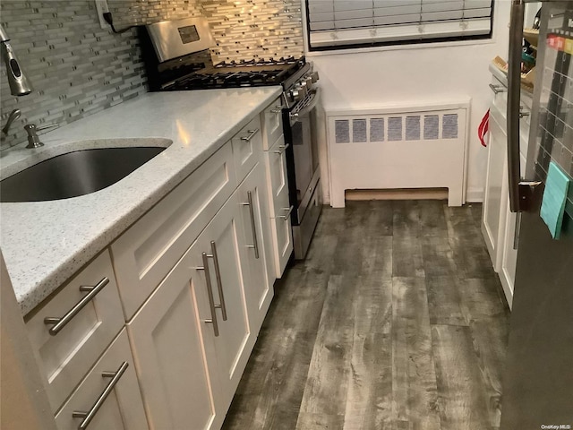 kitchen featuring dark hardwood / wood-style flooring, tasteful backsplash, light stone counters, radiator heating unit, and stainless steel range with gas cooktop