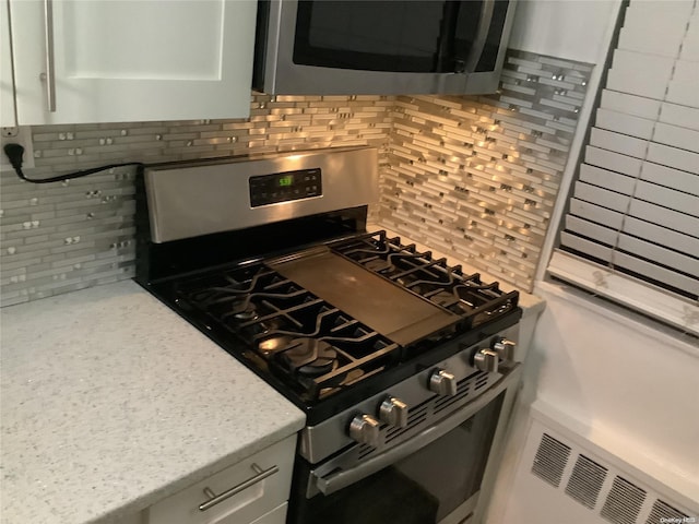 kitchen featuring decorative backsplash, stainless steel appliances, and light stone counters