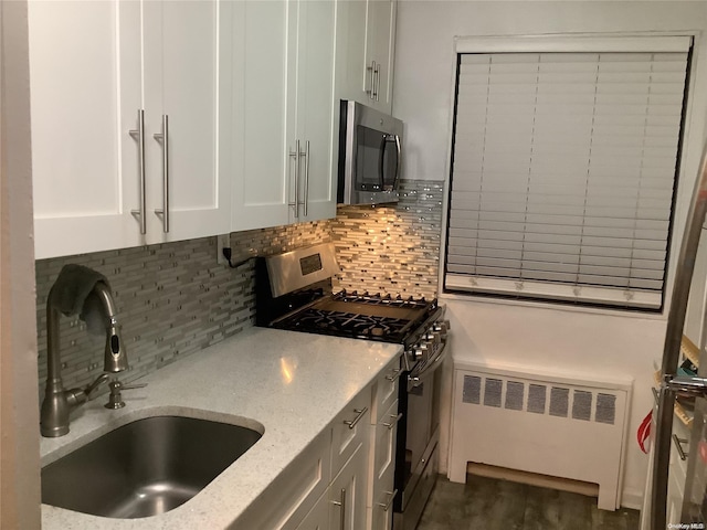 kitchen with light stone countertops, radiator heating unit, white cabinets, and stainless steel appliances