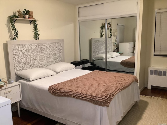 bedroom with dark hardwood / wood-style flooring, a closet, and radiator heating unit