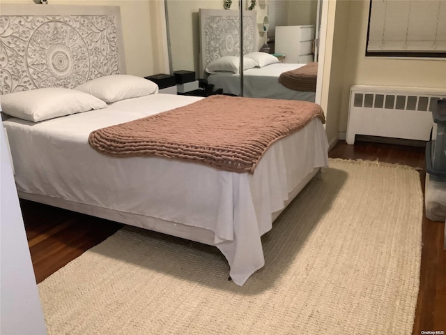 bedroom with hardwood / wood-style flooring, radiator, and a closet