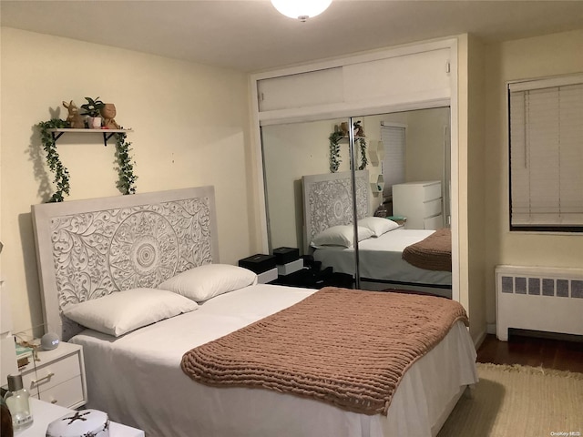 bedroom featuring a closet, radiator heating unit, and hardwood / wood-style floors