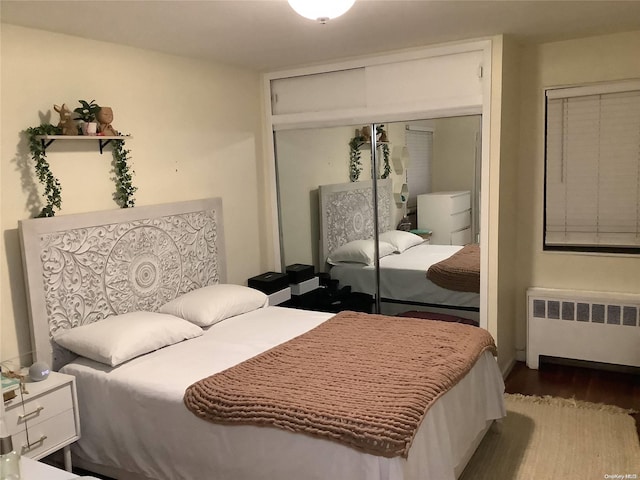 bedroom with hardwood / wood-style floors, radiator, and a closet