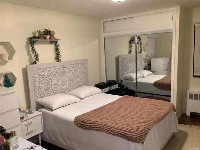 bedroom with hardwood / wood-style flooring, radiator, and a closet