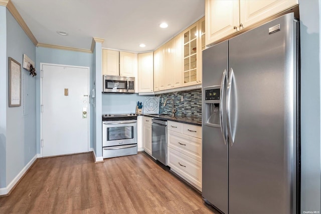 kitchen featuring sink, stainless steel appliances, backsplash, crown molding, and wood-type flooring