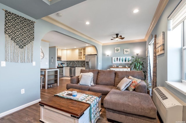 living room featuring dark hardwood / wood-style flooring, an AC wall unit, ceiling fan, and crown molding