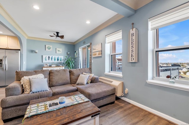 living room featuring a wall mounted AC, wood-type flooring, ceiling fan, and ornamental molding