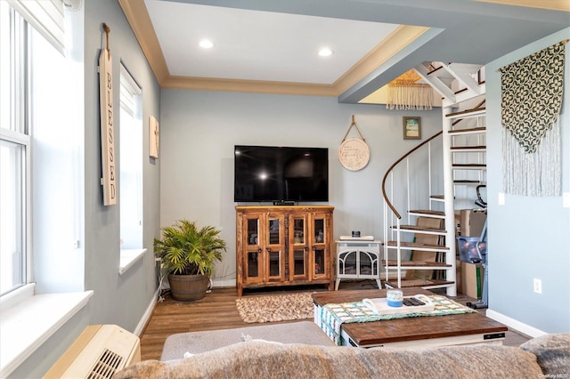 living room with a wealth of natural light, crown molding, and light hardwood / wood-style floors