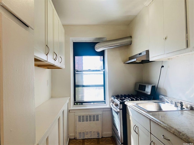 kitchen featuring radiator, gas stove, sink, exhaust hood, and white cabinets