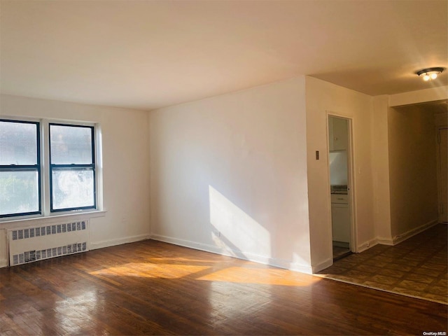 spare room with dark hardwood / wood-style flooring and radiator